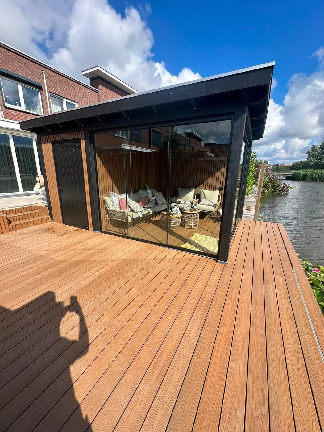 Zwarte tuinkamer met vlonder aan het water